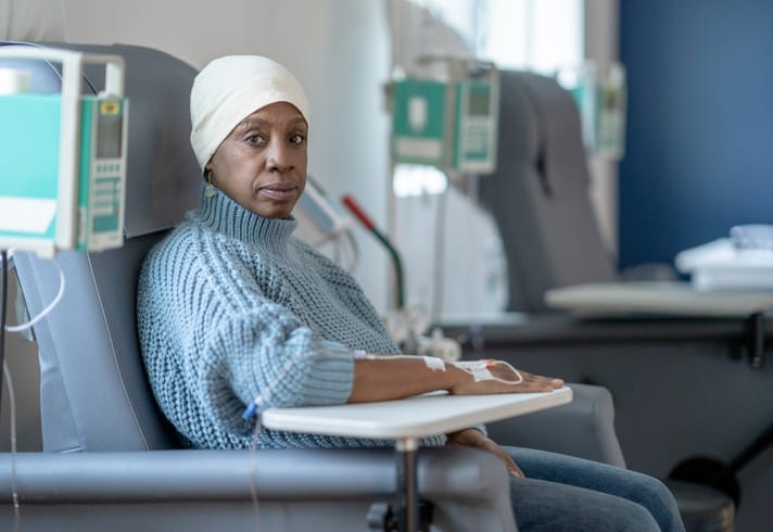 A woman is monitored recovers from chemotherapy in a clinic chair.