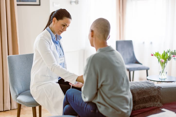 Photo shows a doctor visiting a woman with cancer in her home/Getty Images