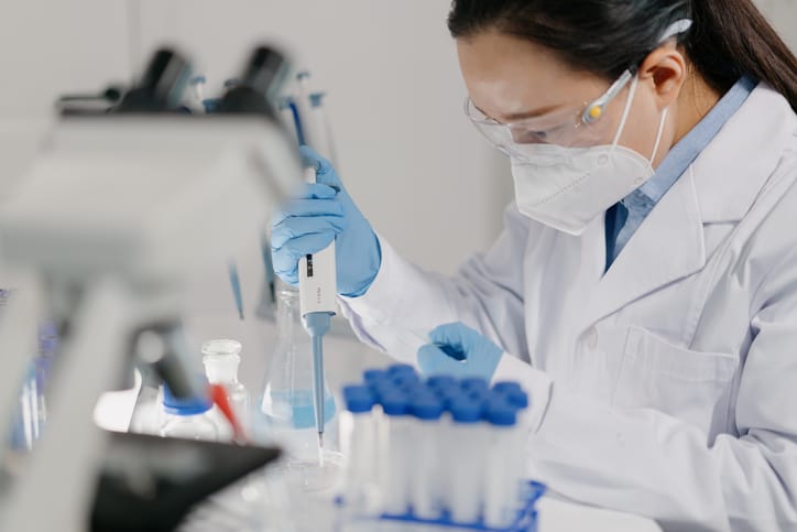 Photo shows a scientist adding reagents to a microscope slide in a laboratory/Getty Images