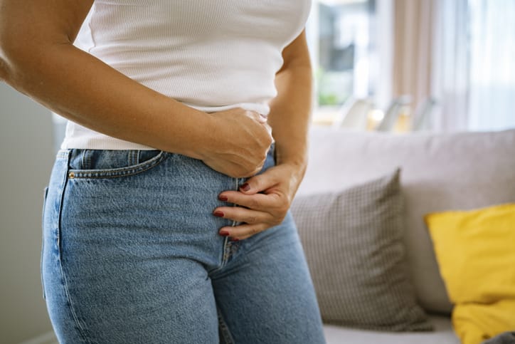Photo shows a woman clutching her lower stomach and pelvis in pain/Getty Images