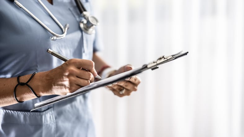 Photo shows a female doctor filling out a medical form on a clipboard/Getty Images