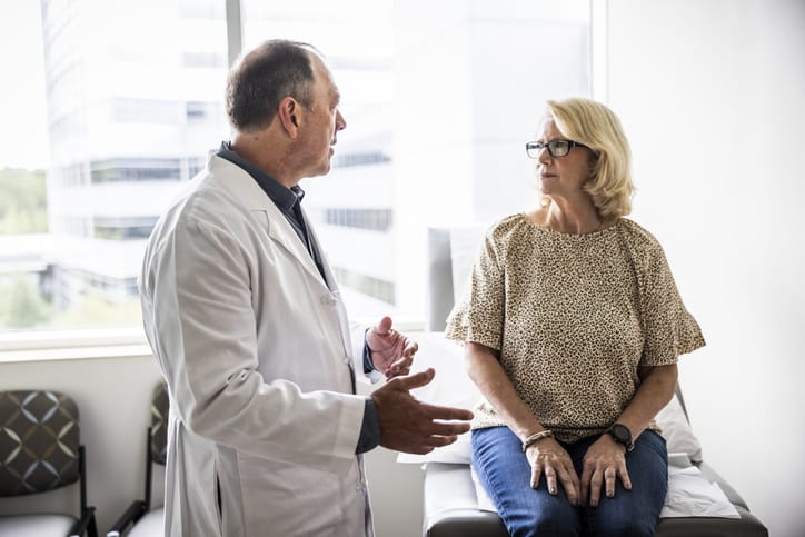 Photo shows a doctor consulting with a senior woman in an exam room/Getty Images