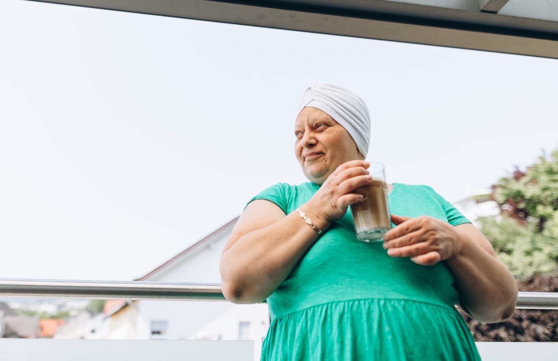 Cancer patient standing outdoors with a cup of iced coffee