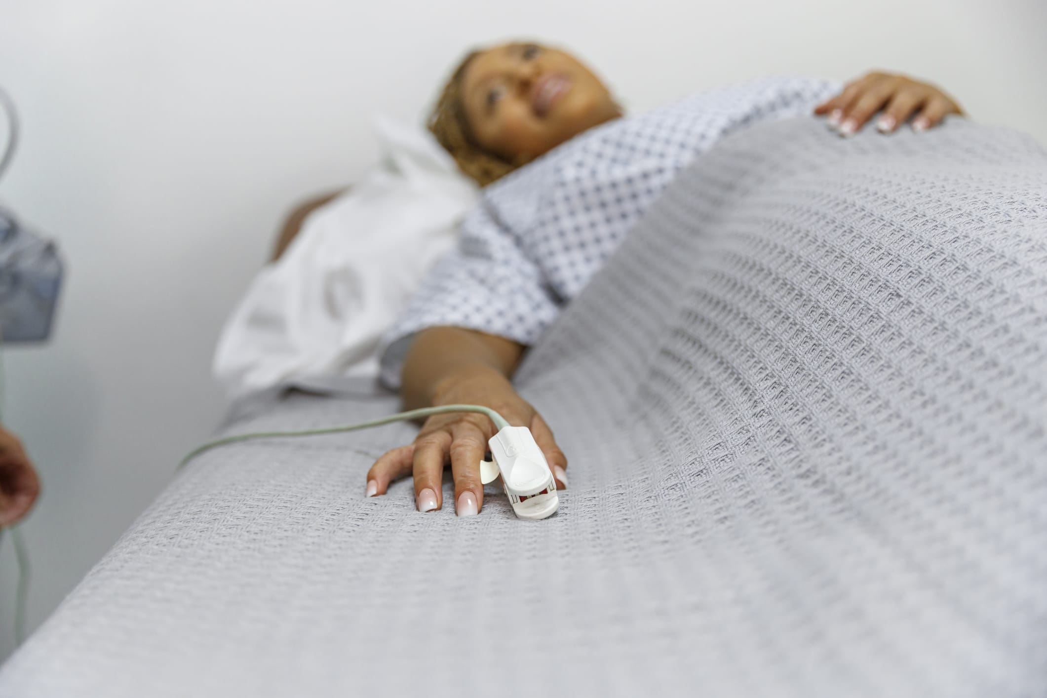 Woman with pulse oximeter in hospital bed