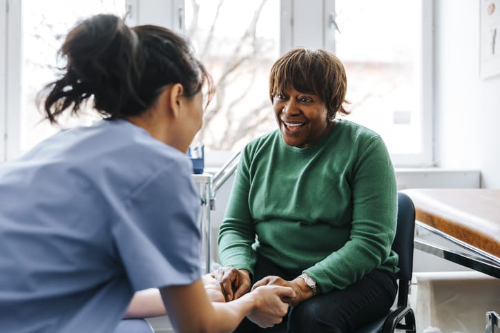 Photo shows a female doctor holding the hands of a senior female patient/Getty Images