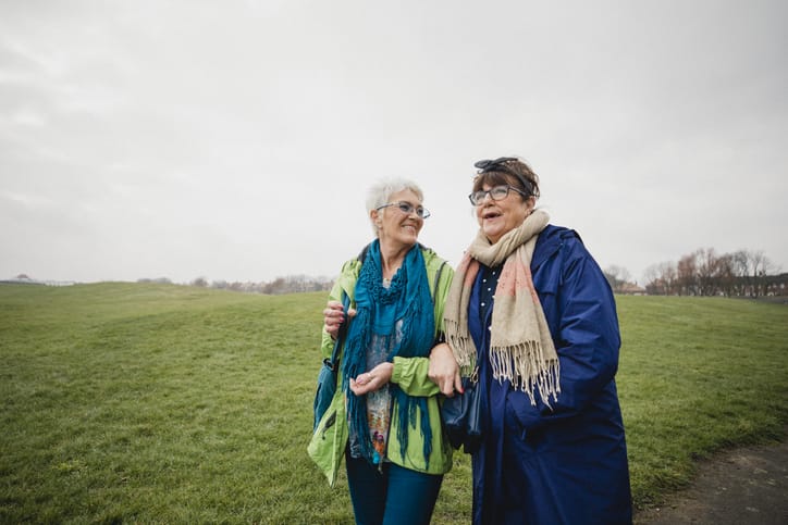 Photo shows two senior women walking in the park together/Getty Images