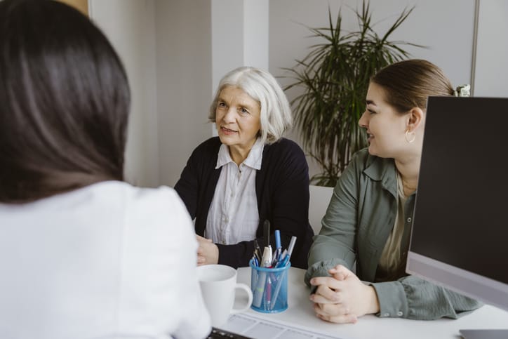 Photo shows an older woman and her daughter meeting with a doctor/Getty Images
