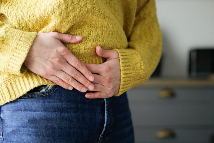 Photo shows a woman holding her stomach in pain/Getty Images