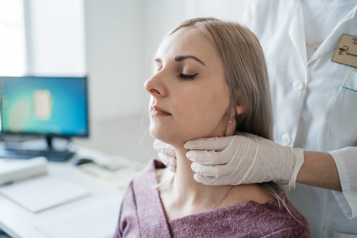Photo shows a doctor examining the thyroid gland of a patient/Getty Images