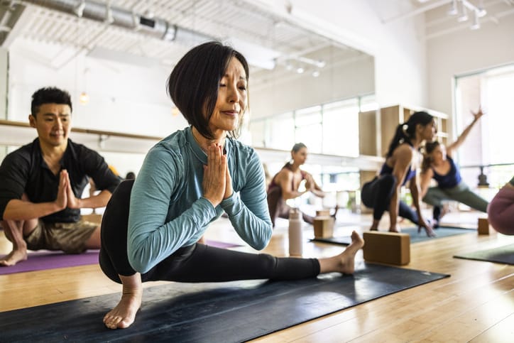Photo shows a group of women practicing yoga in a studio/Getty Images