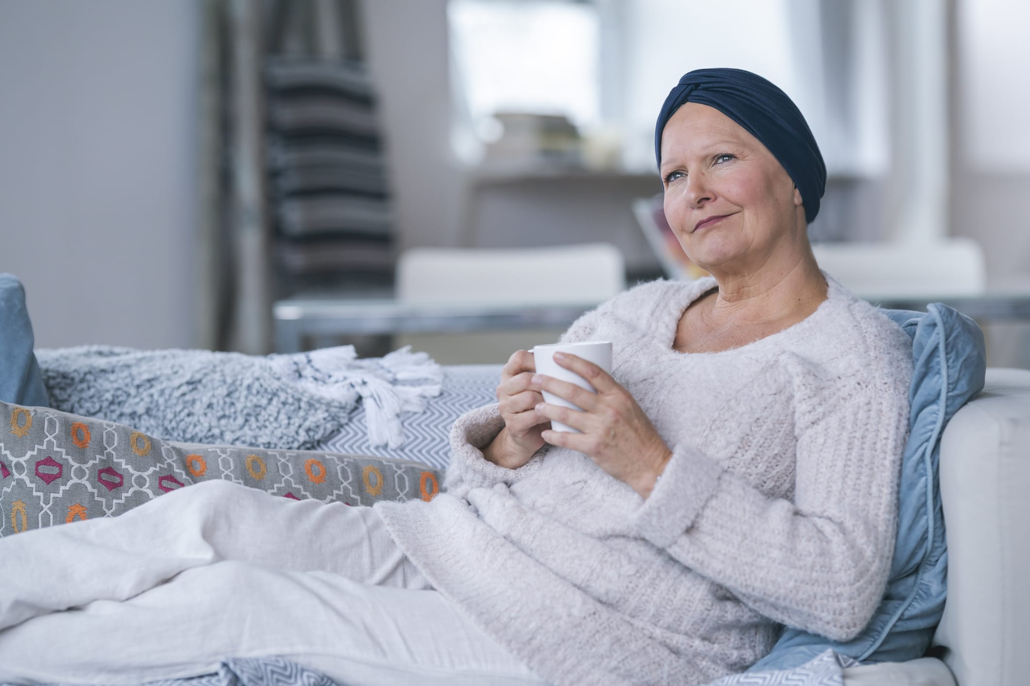 Woman wearing a headscarf lying on couch holding a mug